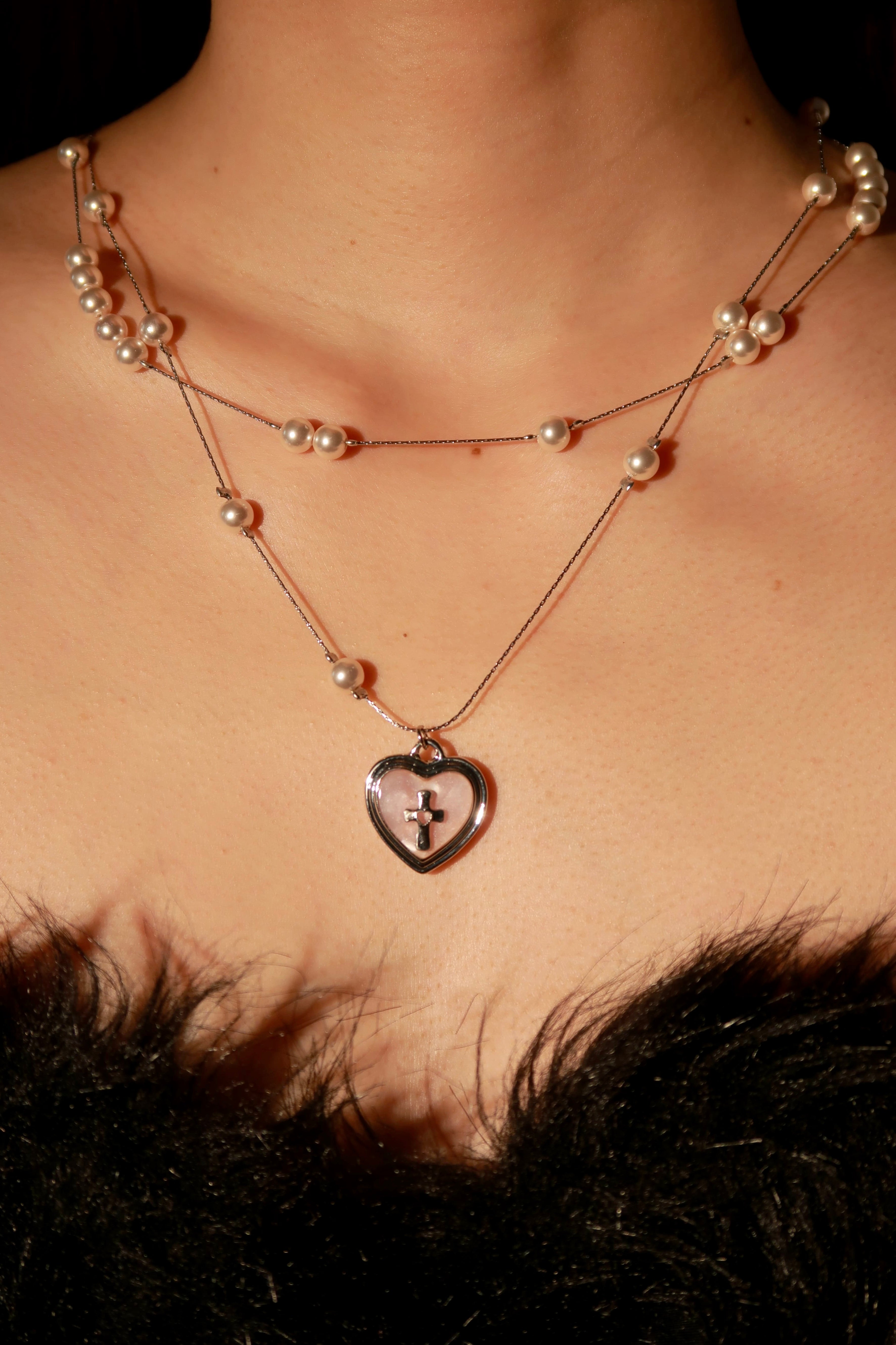 Necklace with a heart-shaped pendant worn by a person, with a blurred background.