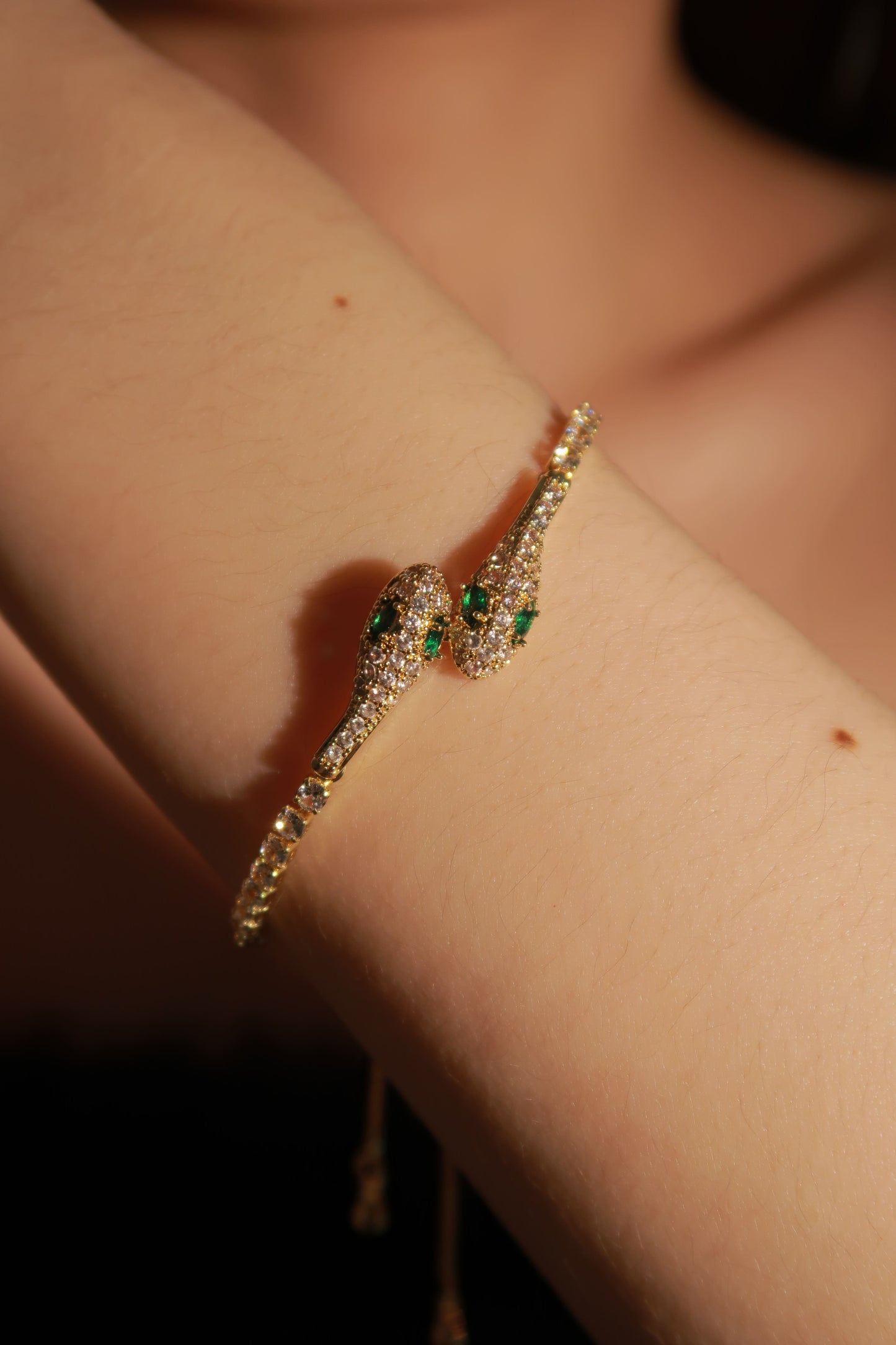 A diamond bracelet with green and white accents displayed on a person's wrist.