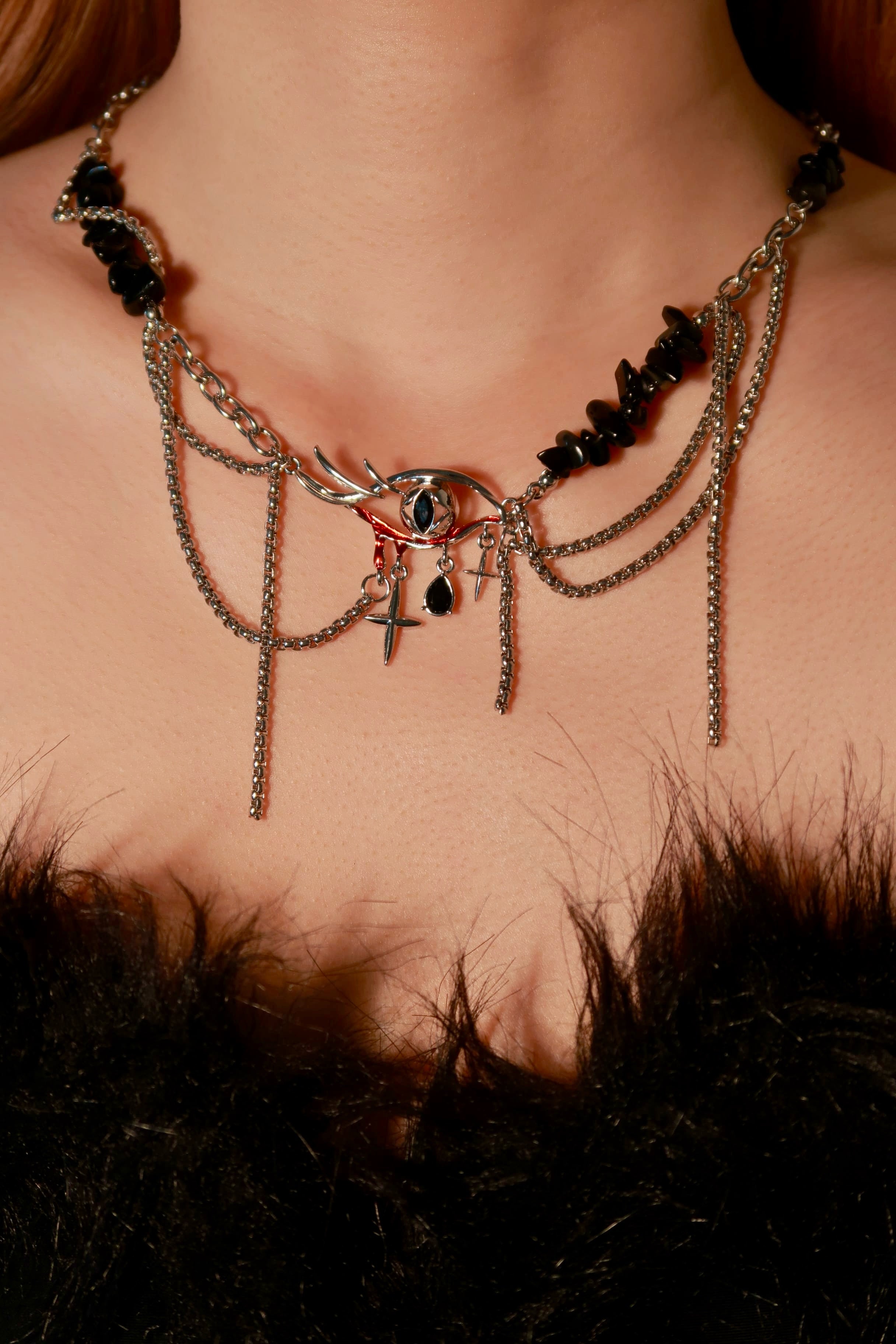 Necklace with black stones and chains on a person's neck against a dark background