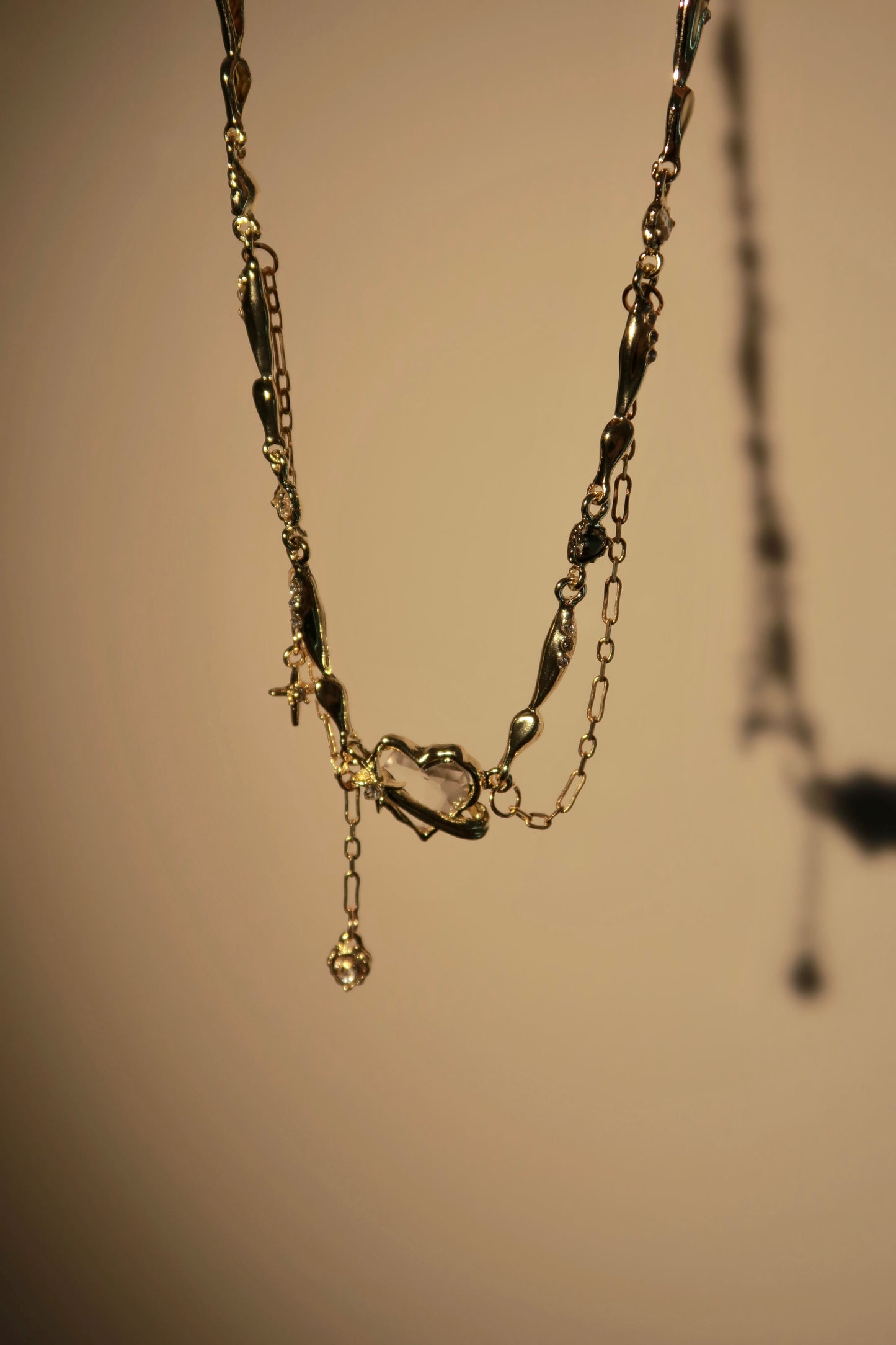 Delicate gold necklace with a small pendant on a beige background