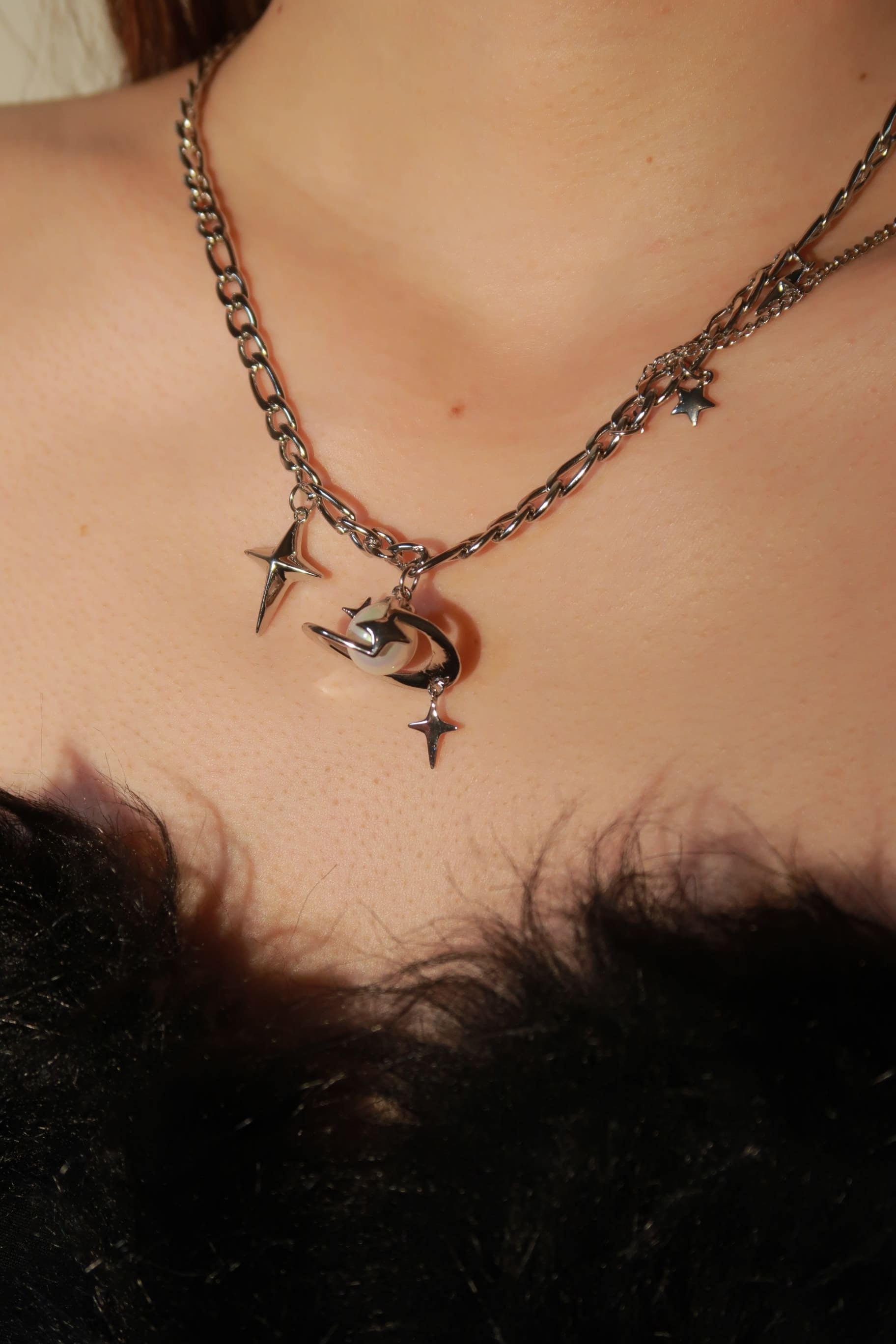 A necklace featuring a series of star charms along a chain, worn by a person.