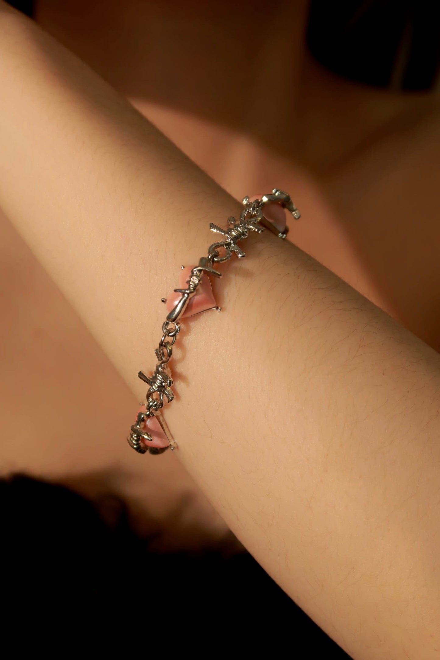 A close-up image of a pink 3D heart bracelet on a person's wrist.