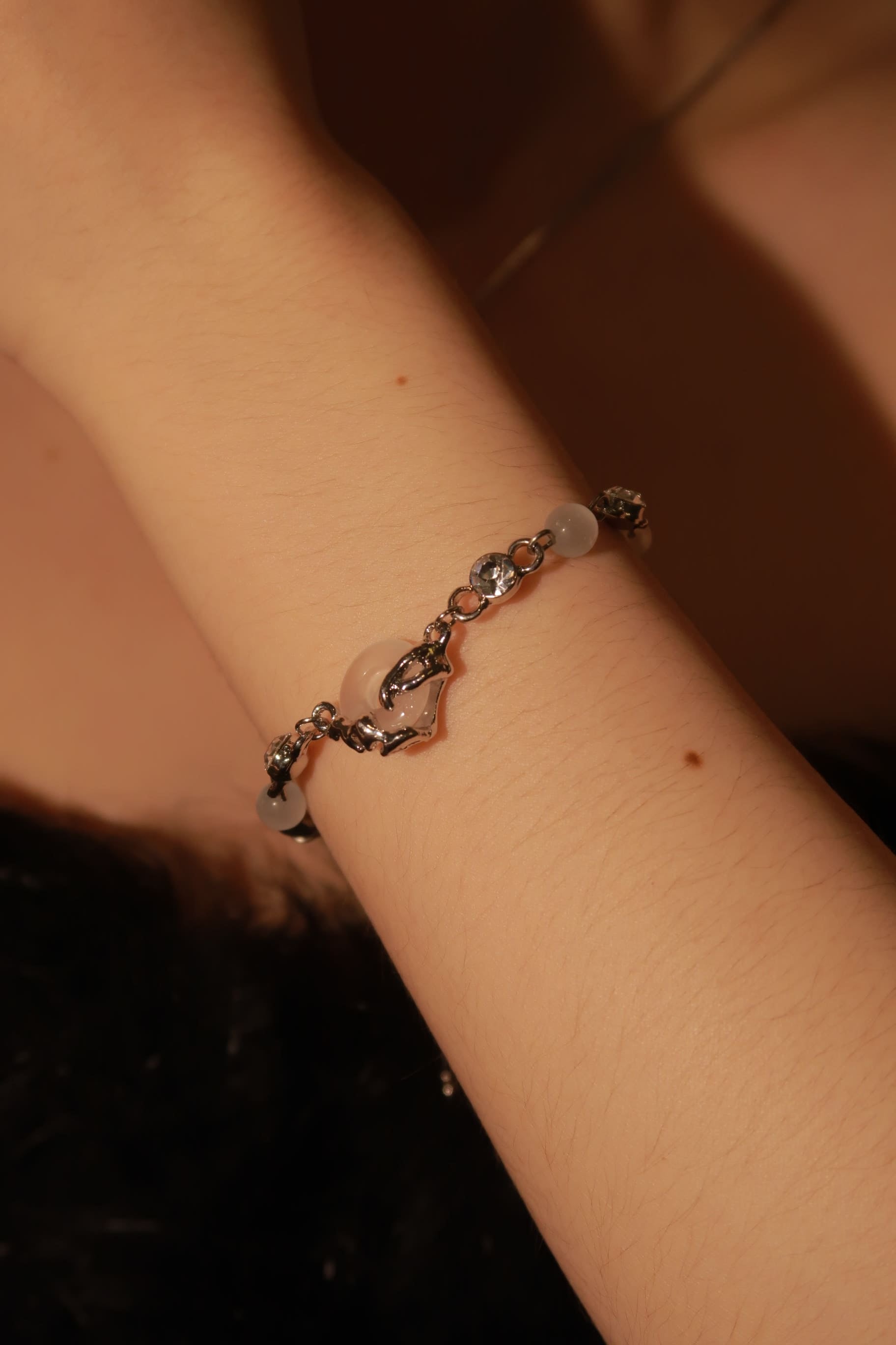 A close-up image of a person wearing a Chinese-style white jade bracelet on their wrist.