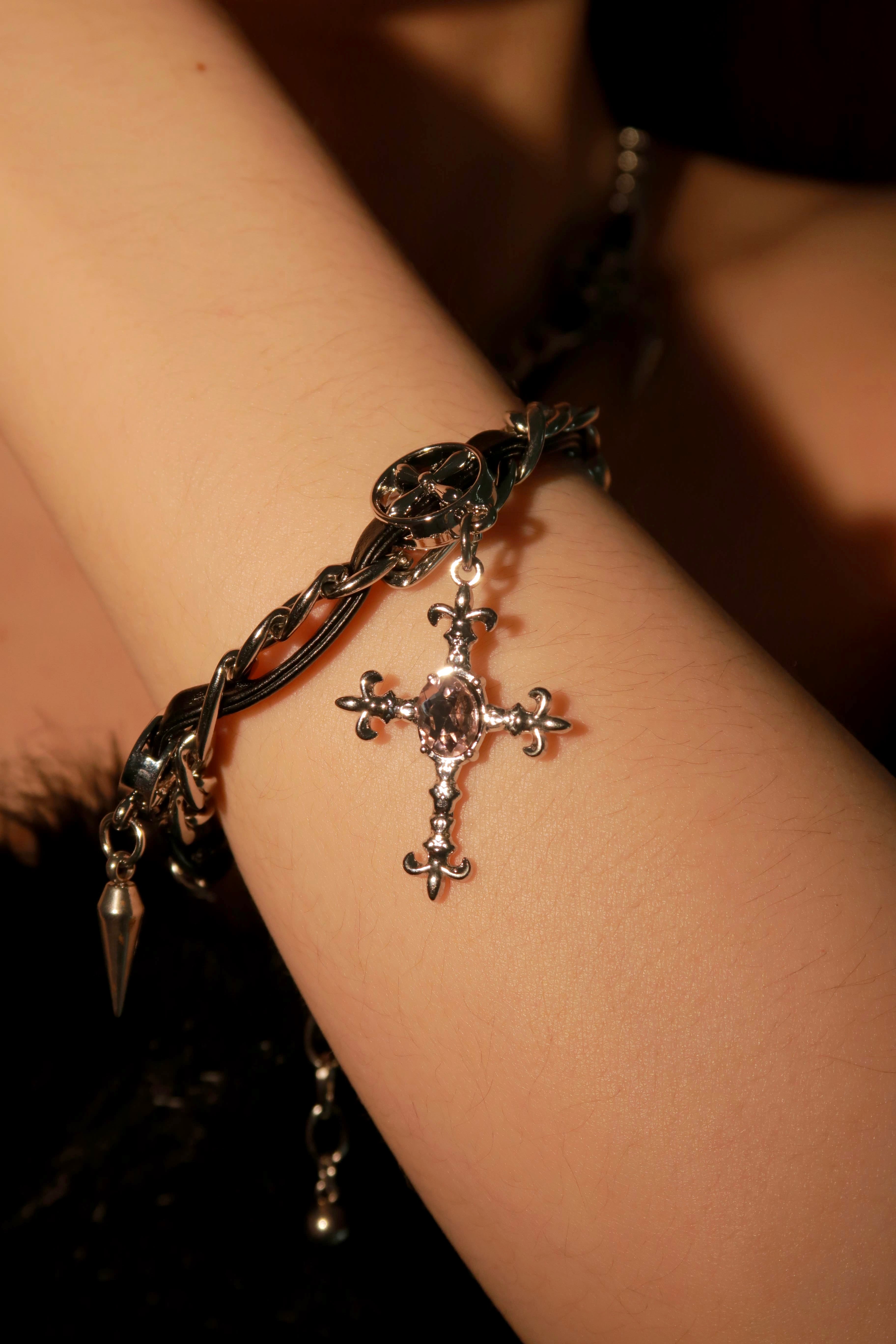 A close-up image of a Gothic Spike Cross Bracelet worn on a person's wrist, showcasing the detailed cross charm and spike accents.