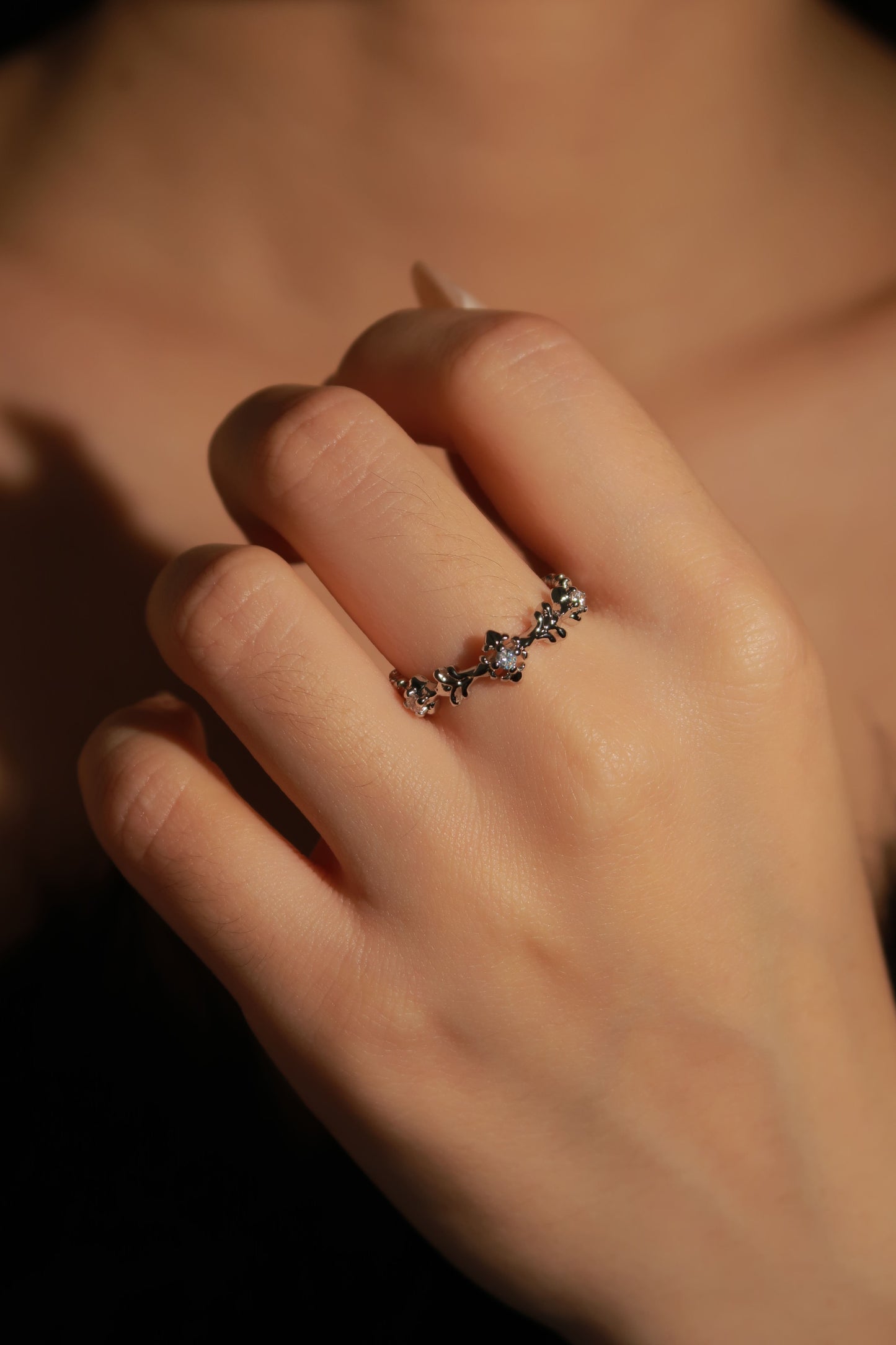 Close-up of a hand wearing a decorative ring with a blurred background