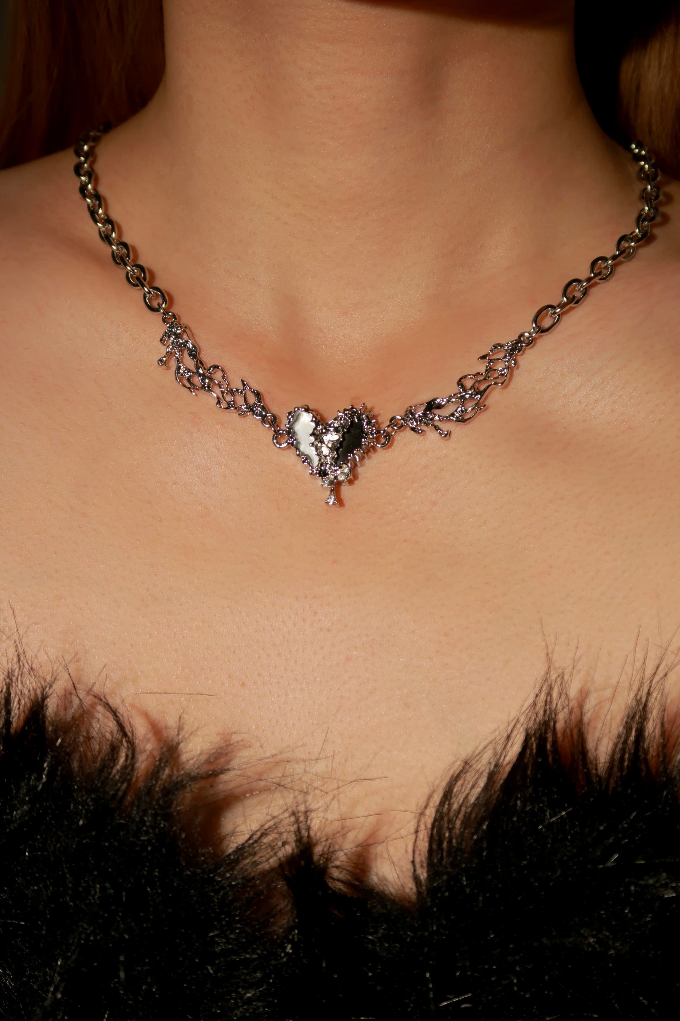 Necklace with a heart-shaped pendant worn by a person against a dark background