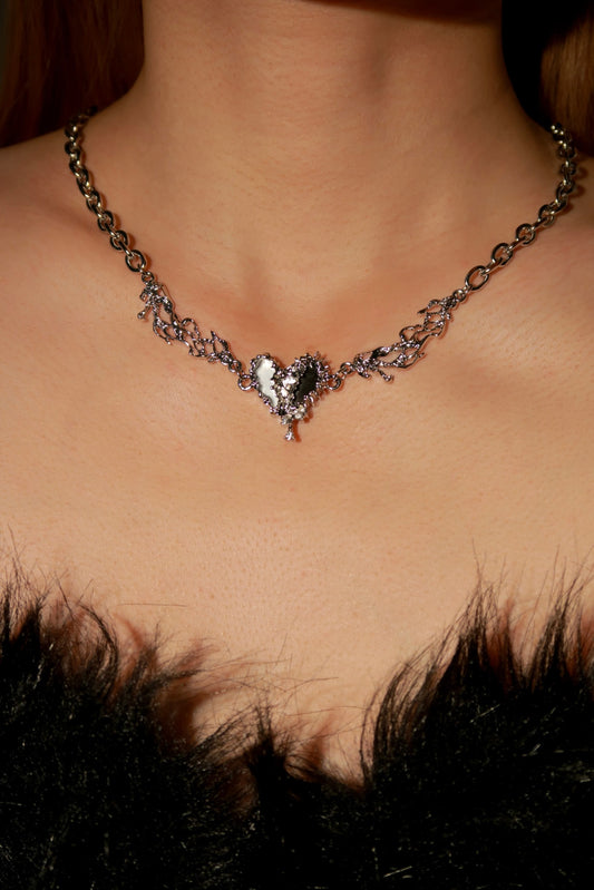 Necklace with a heart-shaped pendant worn by a person against a dark background