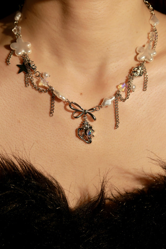 Close-up of a decorative necklace with floral and bow designs on a person wearing a black fur garment.