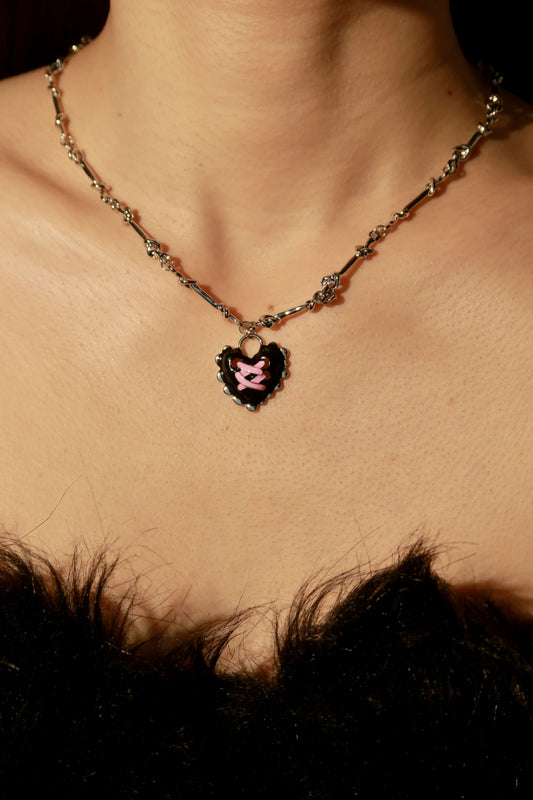 Necklace with a heart-shaped pendant worn by a person, with a blurred background.