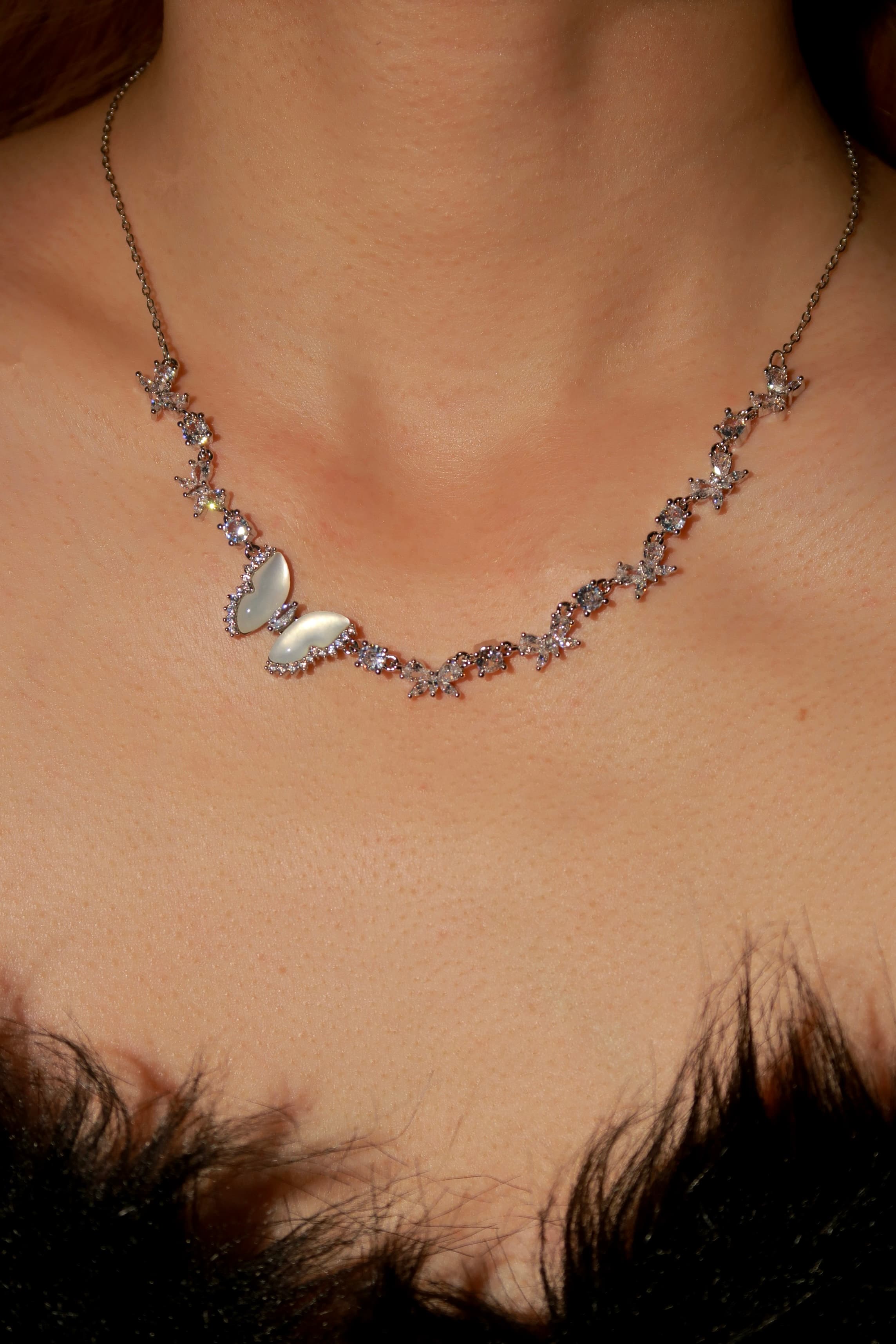 Necklace with butterfly pendant on a person's neck