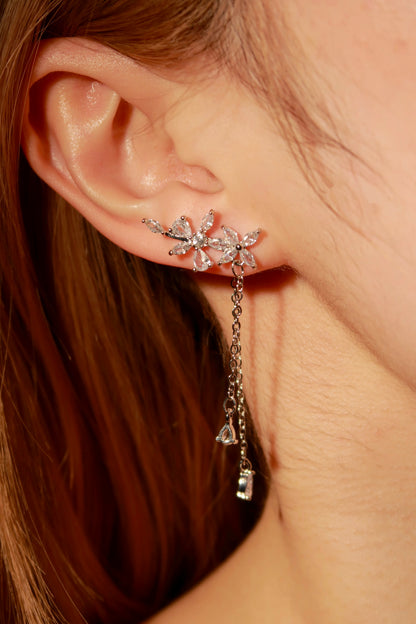 Close-up of a person wearing a floral earring with dangling crystals.