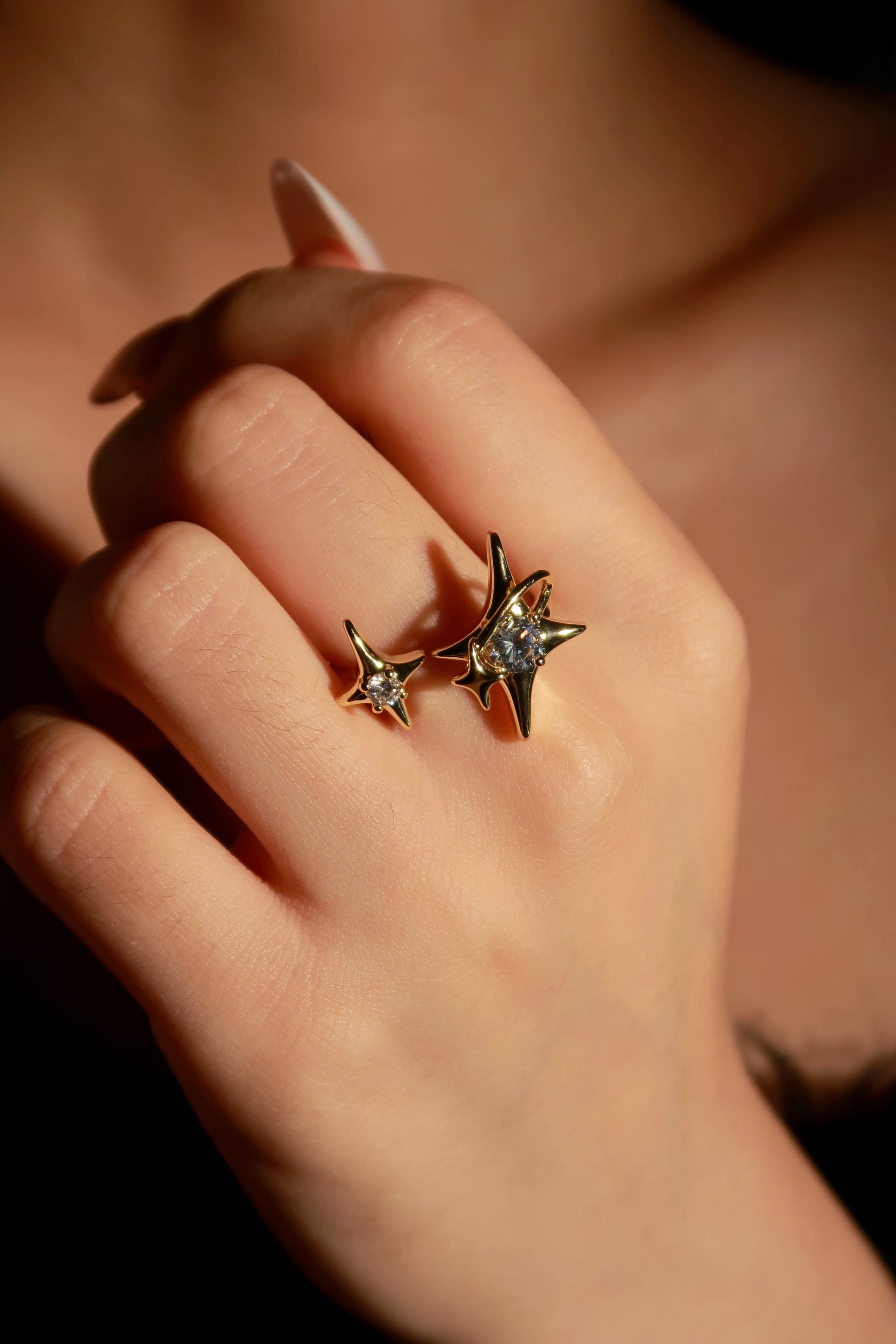 Star-shaped earrings on a hand with a warm background