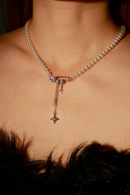 Pearl necklace with star pendant on a person wearing a black feathered garment.
