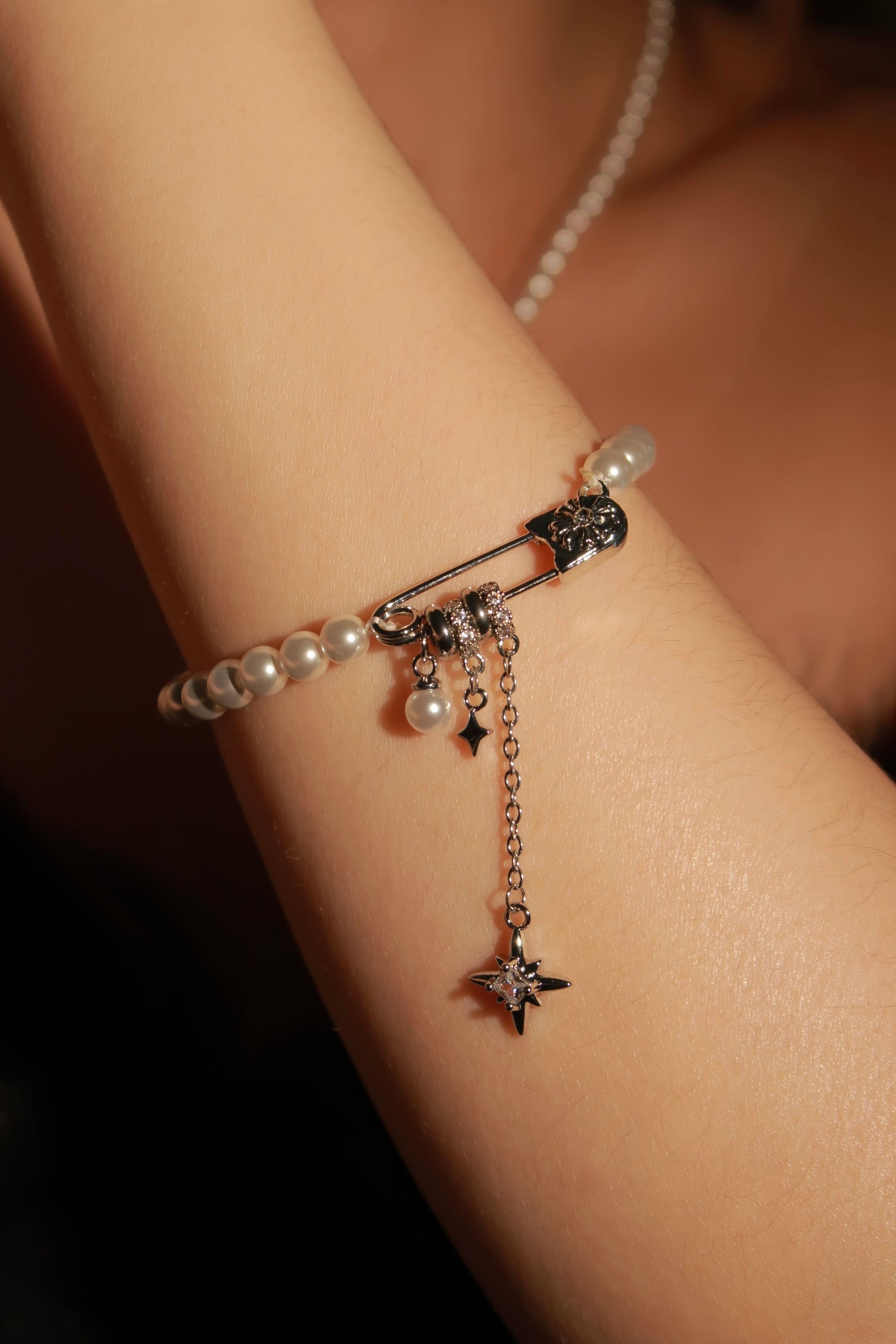 Close-up of a wrist wearing a delicate bracelet with pearls and star charms.