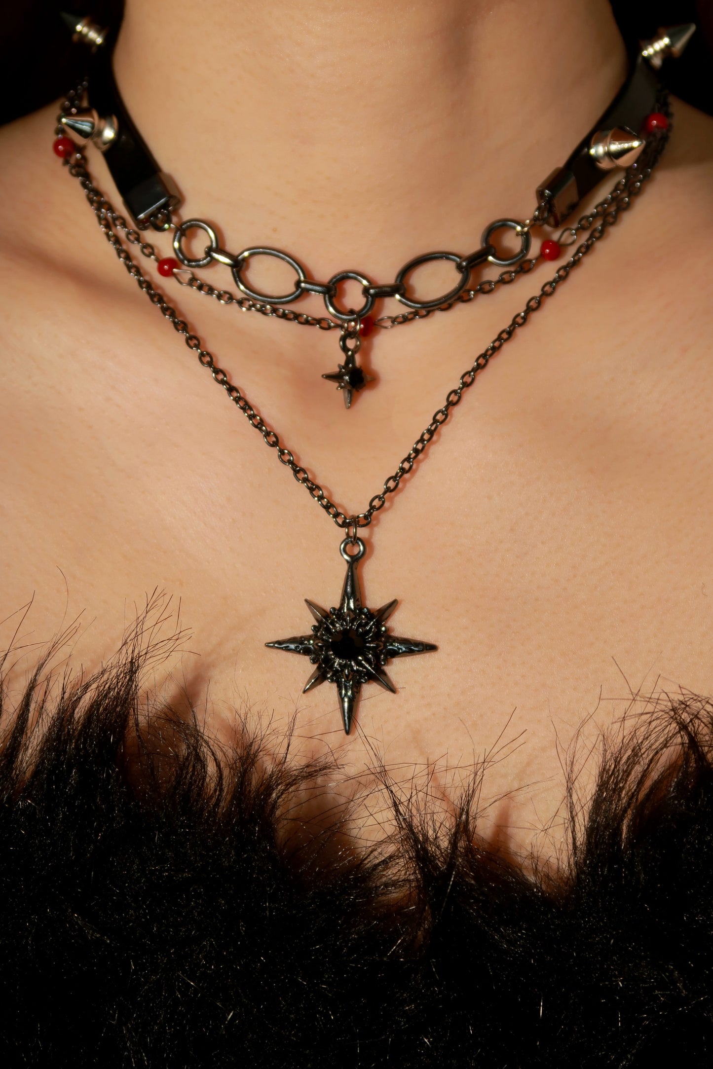 Close-up of a person wearing a chain necklace with a star pendant on a dark background