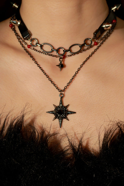 Close-up of a person wearing a chain necklace with a star pendant on a dark background