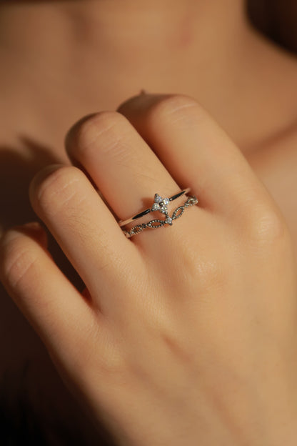 Close-up of a hand wearing a silver ring with a diamond on a blurred background