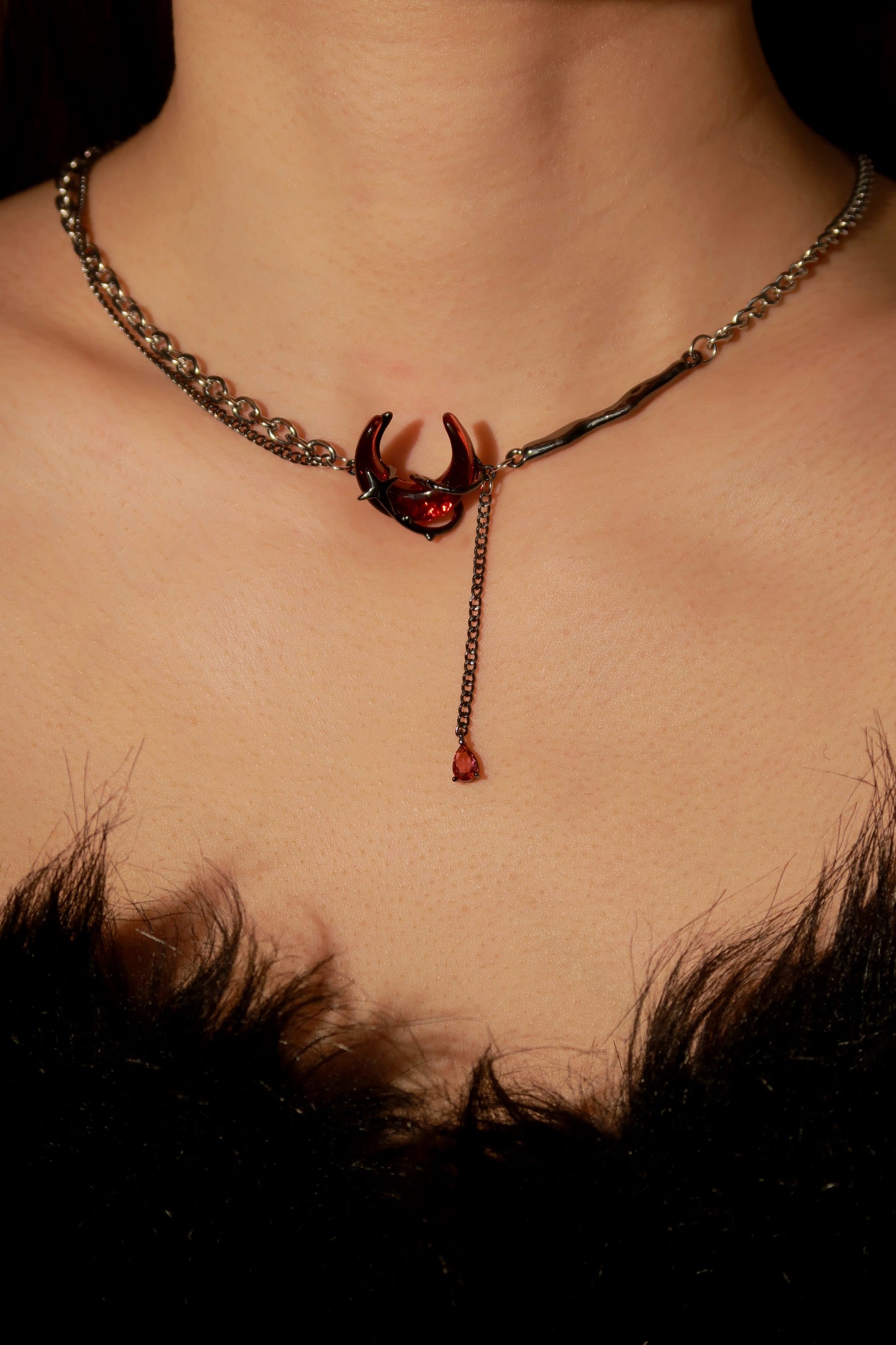 Necklace with a red gemstone pendant on a person's neck against a dark background