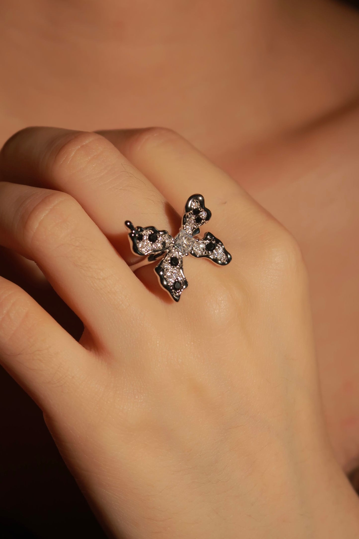 Close-up of a hand wearing a decorative ring with black and white stones.