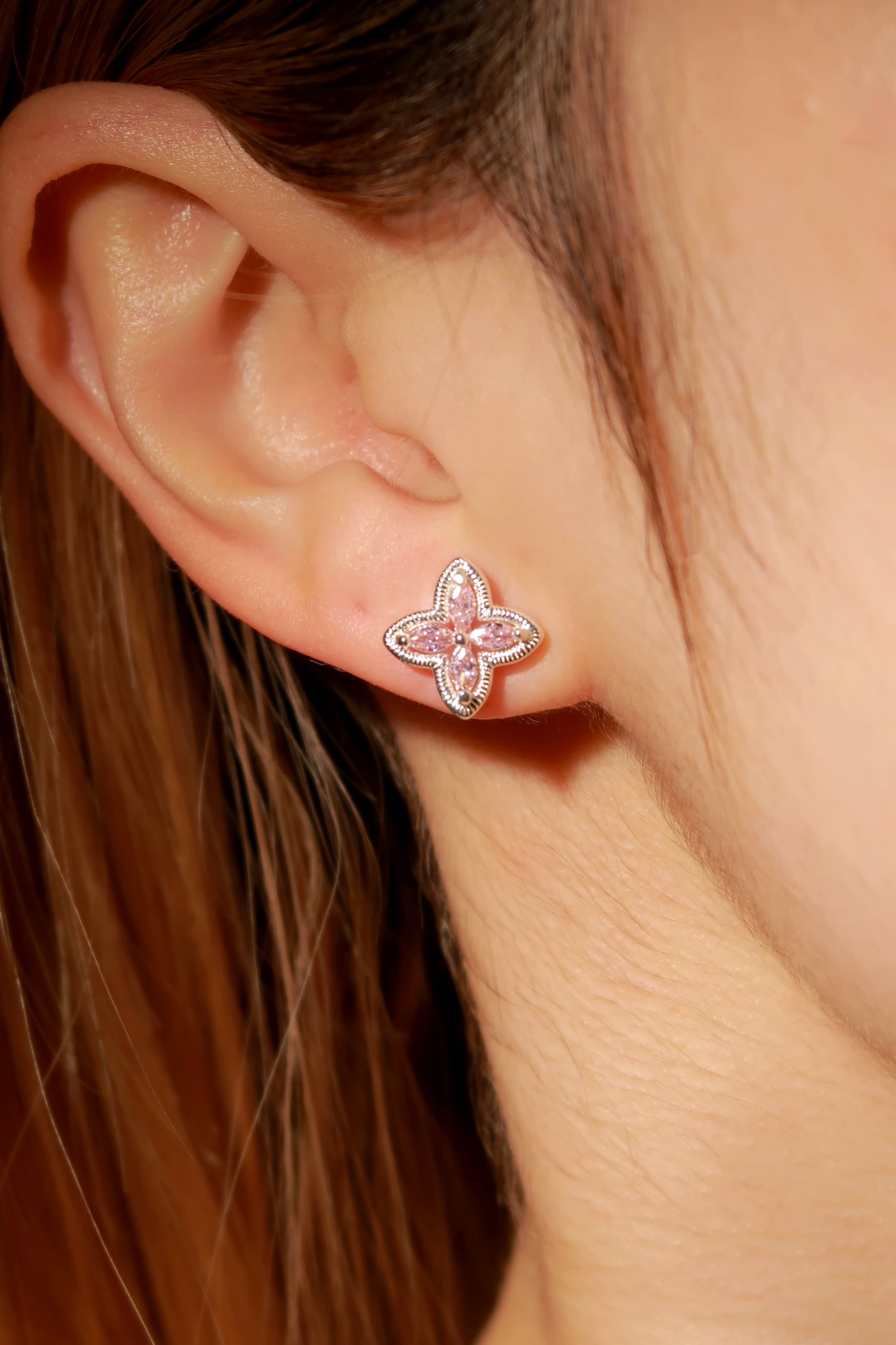 Close-up of a person wearing a pink butterfly earring.