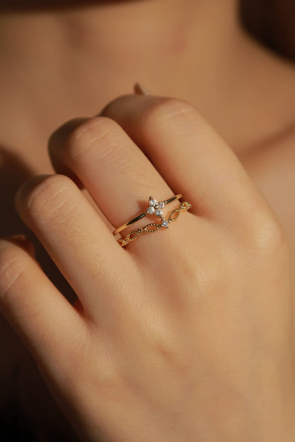 Close-up of a hand wearing two gold rings with star designs on a blurred background