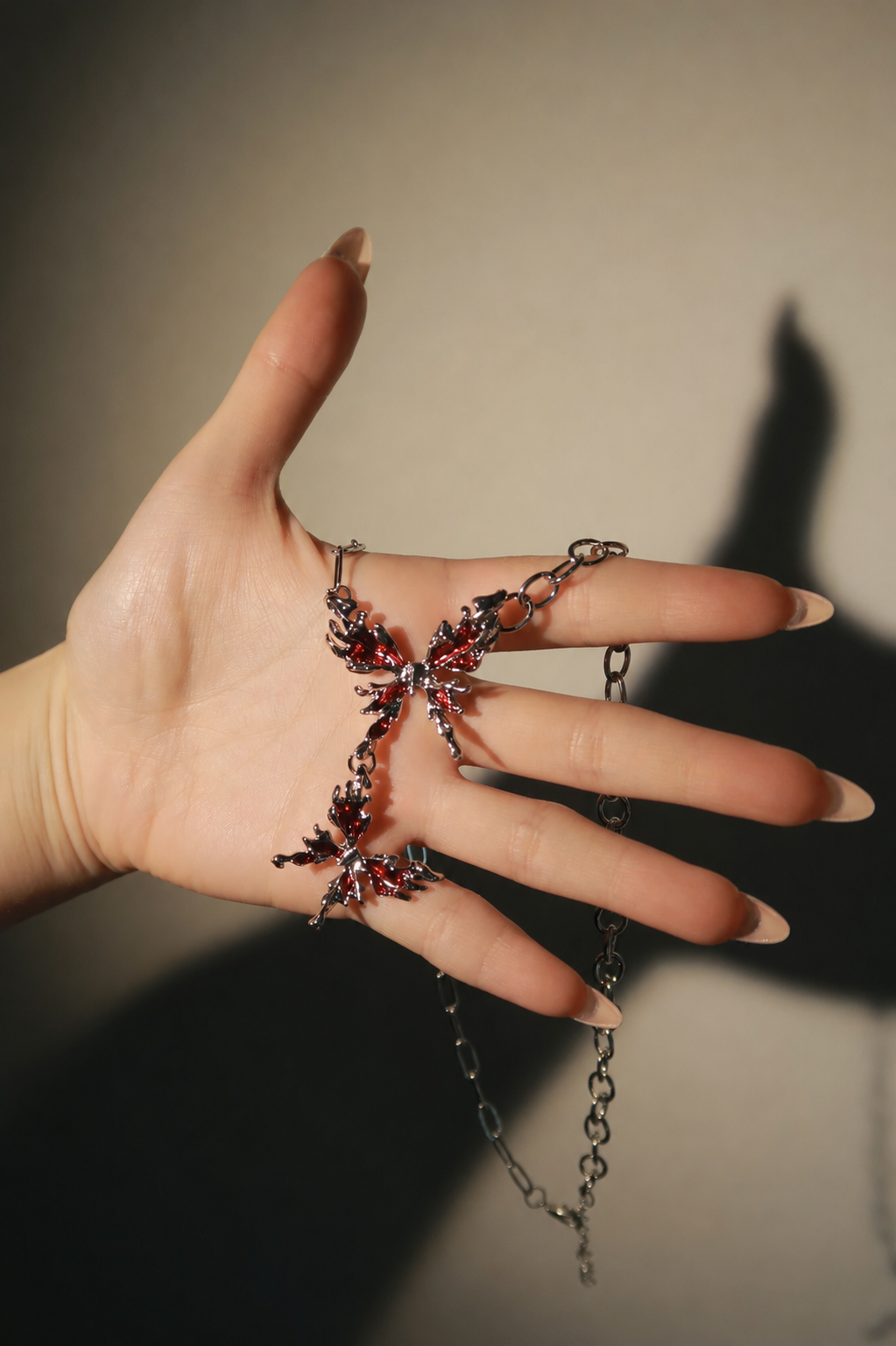 Hand wearing a decorative ring with chain details on a neutral background