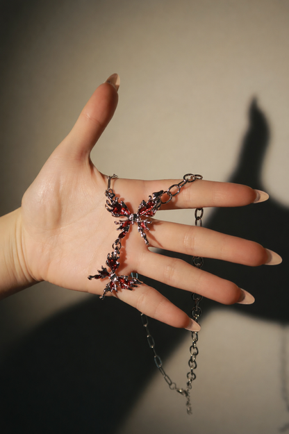 Hand wearing a decorative ring with chain details on a neutral background