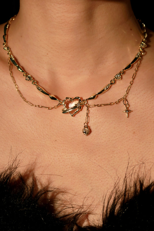 Close-up of a person wearing a gold necklace with heart and star charms.
