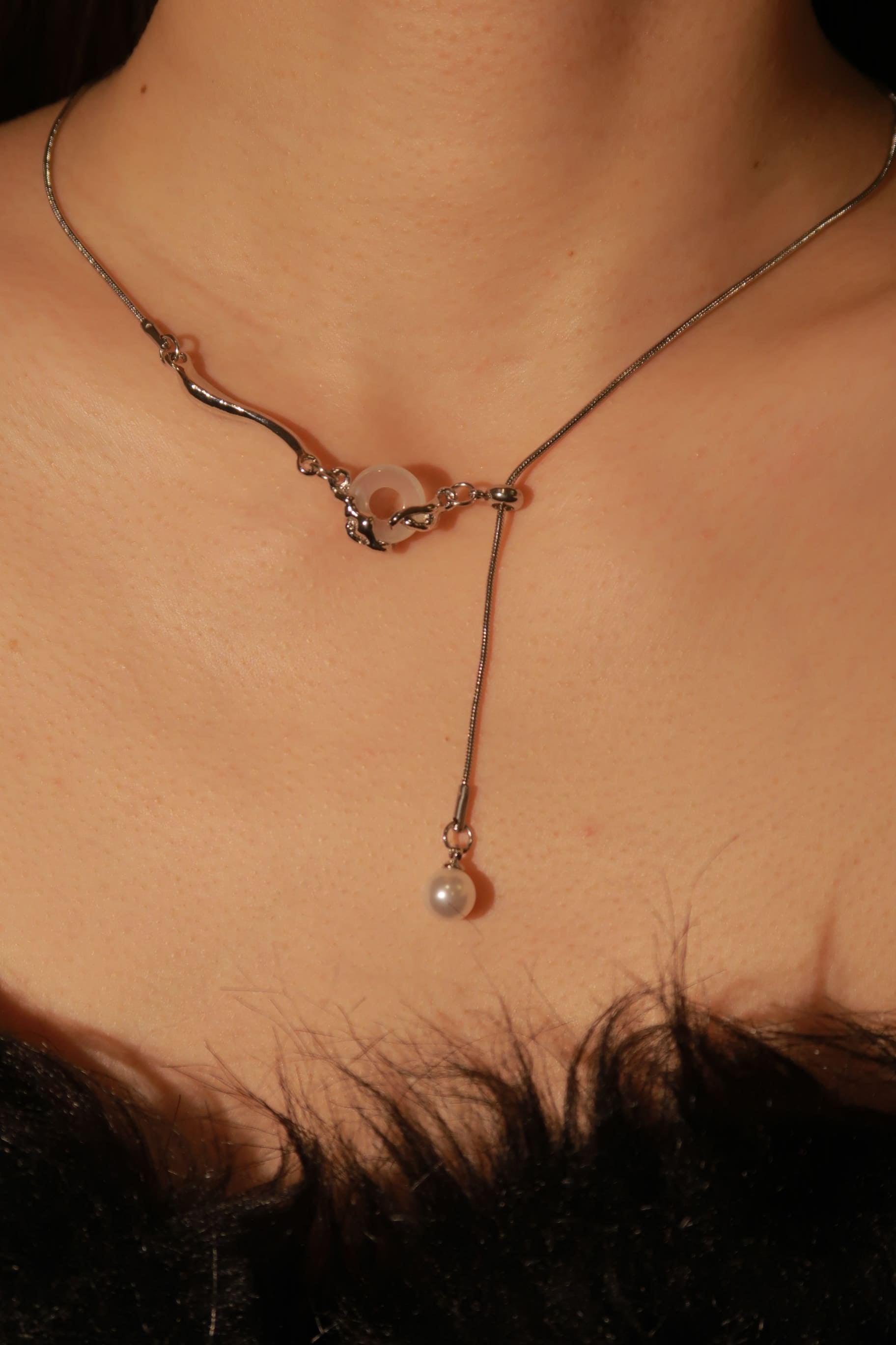 A Chinese-style white jade necklace with a pearl pendant, displayed on a person's neck.