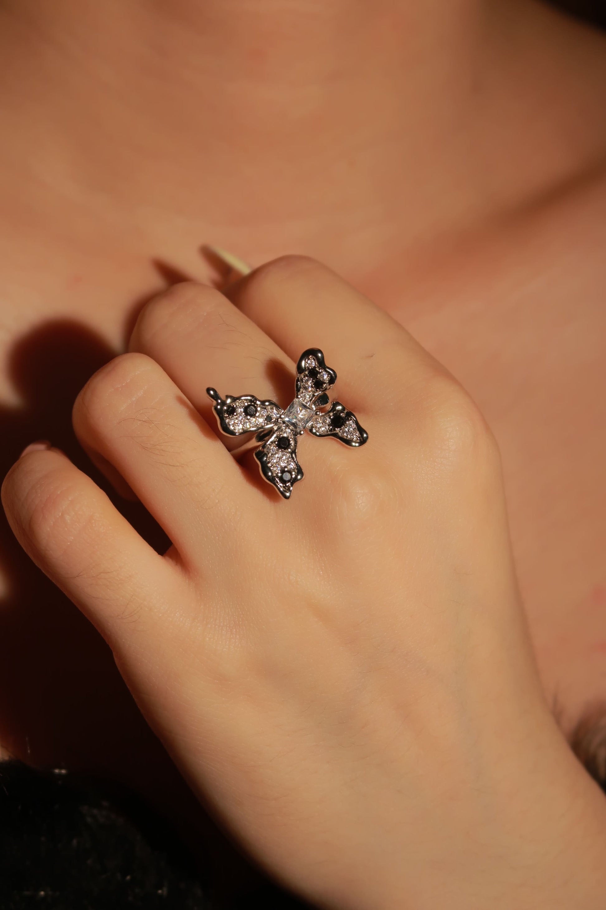 Close-up of a hand wearing a decorative ring with a blurred background